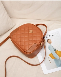 Brown quilted crossbody bag with gold floral buckle, handle, and magazine prop