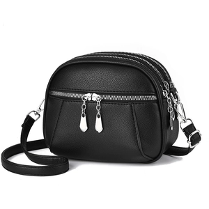Black PU leather crossbody bag with lychee texture and triple zipper design on white background