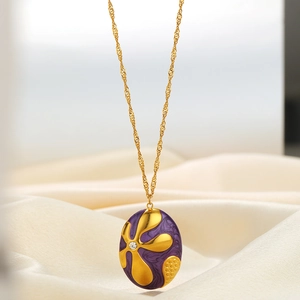 Gold oval pendant necklace with purple flower pattern and small diamond on silk background