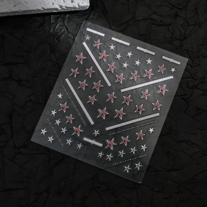 Macro shot of 3D star nail art stickers with silver patterns on black textured background