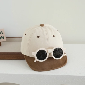 Détail de casquette bébé avec trous d'aération brodés et lunettes de soleil rondes déco