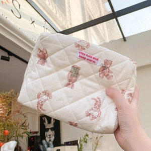 Forest bear quilted cotton makeup bag held by hand in a stylish indoor setting