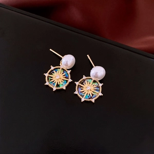 Close-up of 18k gold plated earrings featuring pearls and starburst shell pendants