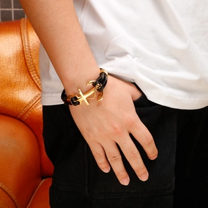 Close-up of golden anchor clasp on multi-layer black braided leather bracelet for men