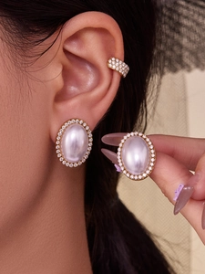 Close-up of elegant oval pearl studs and zircon ear cuffs in 18k gold plating on a model