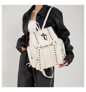 Detail showing cream PU leather backpack with silver studs and cross pendant detail