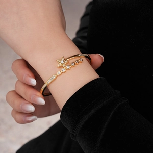 Close-up of a gold-plated star bracelet with sparkling zircon on a model's wrist
