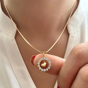 Collier coeur doré minimaliste avec cristaux scintillants porté sur une chemise blanche