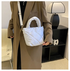 White quilted bucket bag with crossbody strap shown over a dark brown winter coat