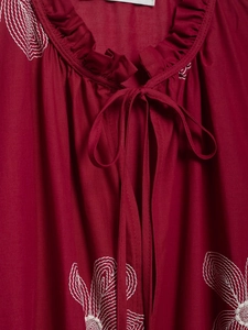 Detail of raspberry embroidered shirt with ruffled neckline and delicate tie closures