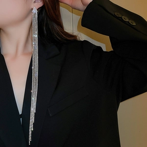 Dettaglio di orecchini a nappa argentati con strass indossati da una modella in abito nero