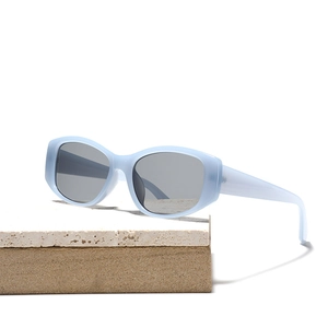 Chic light blue transparent square sunglasses with grey lenses on a stone base