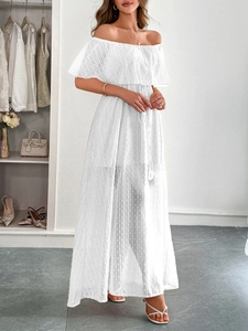 Dettaglio dell'abito lungo bianco con spalle scoperte, trama a pois e scollo a balze