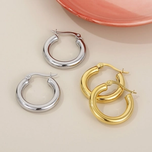 Chic polished stainless steel hoop earrings in gold and silver finish set on a beige background