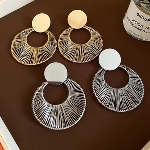 Macro detail of geometric round earrings with fine wire-wrap in gold and silver finish