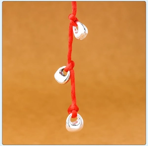 Macro shot of three S925 sterling silver water-drop pendants on a red woven cord