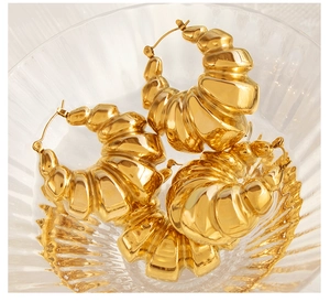 Macro shot of 18K gold plated croissant earrings with textured ridges in a glass bowl