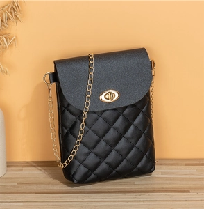 Detail of black quilted leather shoulder bag featuring a gold oval twist lock and chain strap