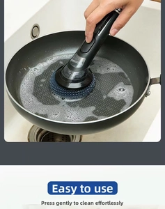 Détail de la brosse à vaisselle avec réservoir nettoyant une poêle avec de la mousse