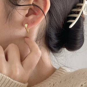 Detail of a minimalist gold fluid teardrop earring worn by a model in a lifestyle shot