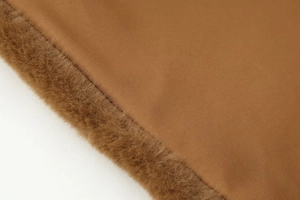 Detailed macro view of the brown faux fur texture and smooth woven fabric stitching