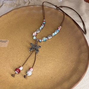 Detail of bohemian woven necklace with butterfly pendant and colorful ceramic beads