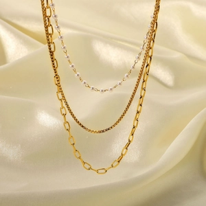 Détail de colliers multicouches plaqués or 18 carats avec perles sur fond de soie
