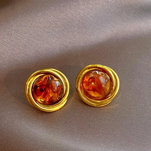 Close-up of vintage resin earrings with golden metal twist on brown satin background