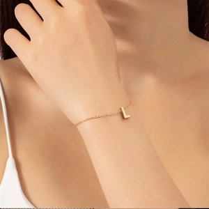 Gros plan d'un pendentif lettre L dorée sur un bracelet à chaîne délicate