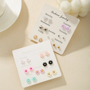 Macro shot of 7-pair daily animal stud earring set on a beige textured background