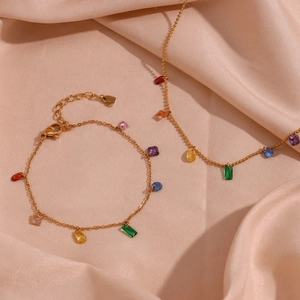 Detail of 18K gold-plated necklace and bracelet with vibrant rainbow gemstones on silk