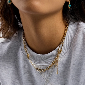 Detailed view of 18K gold-plated necklace with cross pendant, pearl and star earring charm