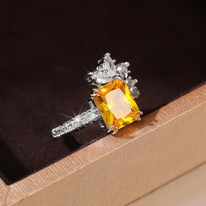 Macro side view of rectangular yellow gemstone ring with pear-shaped diamonds and silver band