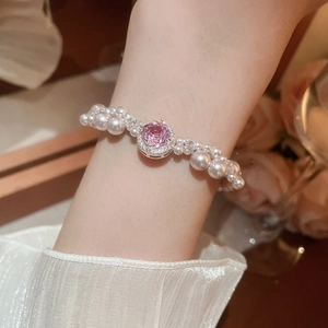 Detail of elegant pearl bracelet featuring a pink gemstone centerpiece on female wrist