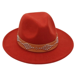 Detail of red wool fedora hat featuring a brown leather band and silver metal rivets