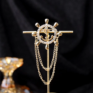 Detail of a gold nautical brooch featuring helm, anchor, and multi-layered chain tassels