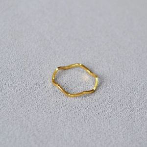 Macro shot of minimalist gold plated wavy ring on grey textured fabric background