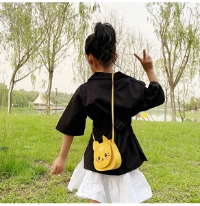Girl wearing a cute yellow cat crossbody bag in a park, showing the mini size and fit