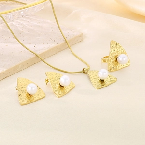 Macro detail of hammered gold jewelry set with white pearls on elegant beige silk background