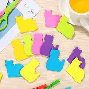 Vibrant cat-shaped sticky notes scattered on desk with colorful stationery and props