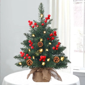Close-up of a tabletop Christmas tree with warm LED lights, berries and pine cones