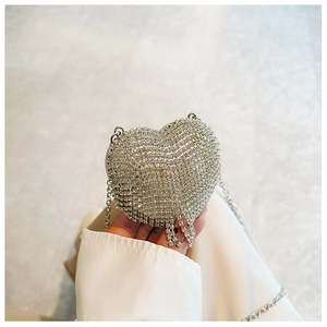 Macro shot of silver heart-shaped evening bag with sparkly rhinestones and fringe detail