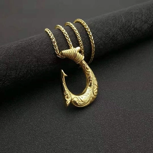 Detailed close-up of golden Viking fish hook pendant with intricate engravings and chain