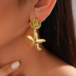 Close-up of a model wearing vintage style golden starfish geometric earrings in a retro design