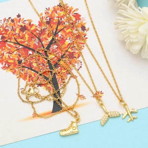 Detail of gold necklaces with sparkling mermaid tail, airplane, and sneaker pendants