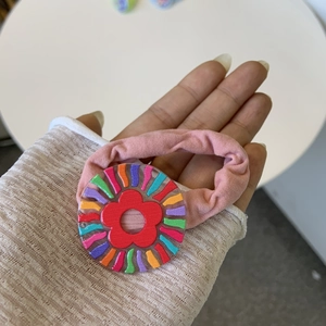 Close-up of pink hair scrunchie with acrylic floral and rainbow striped charm