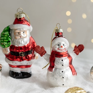 Christmas glass ornaments featuring Santa Claus and snowman figurines on white snow