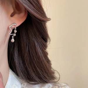 Close-up of a silver liquid metal style earring with an irregular wave design on model
