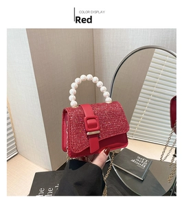 Detail of red sequined handbag featuring a white pearl top handle and golden chain strap