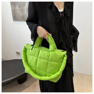 Detail of neon green quilted puffer tote bag with glossy finish and secure zipper closure